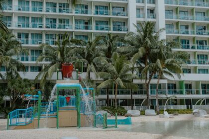 familotel sonnenpark - A vibrant playground at a tropical resort with palm trees and a modern buildi