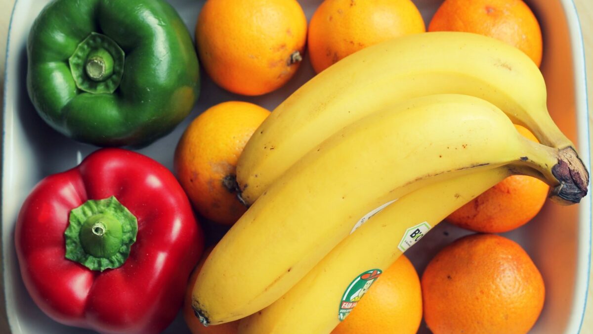 Vibrant mix of fruits and vegetables, including bananas and peppers, in a bowl.