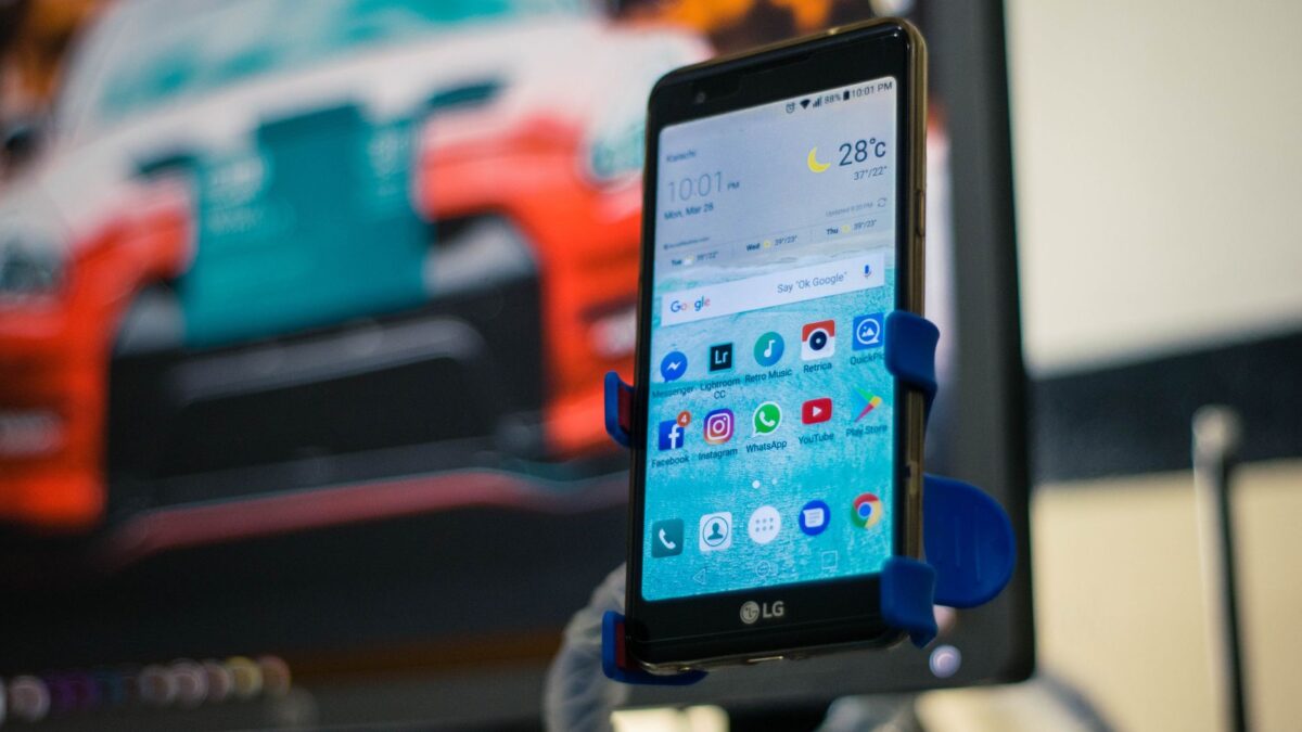 Smartphone mit Carsharing-App neben einem Auto