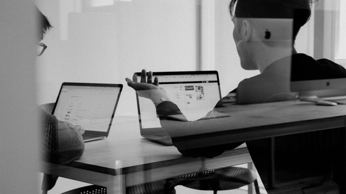 Zwei Personen analysieren Kursdaten und Handelsplattformen am Laptop im Büro